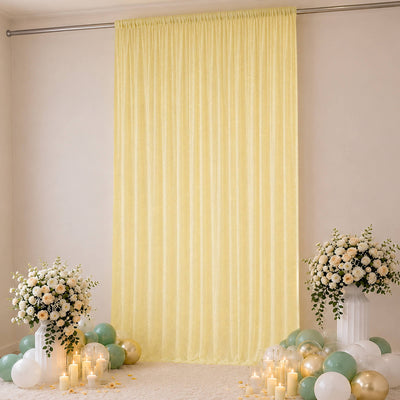 Elegant yellow draped backdrop with floral arrangements and pastel balloon decor