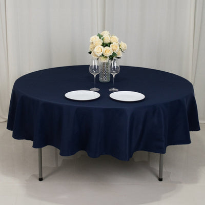 Navy round tablecloth on a table set for dinner with plates and glasses.