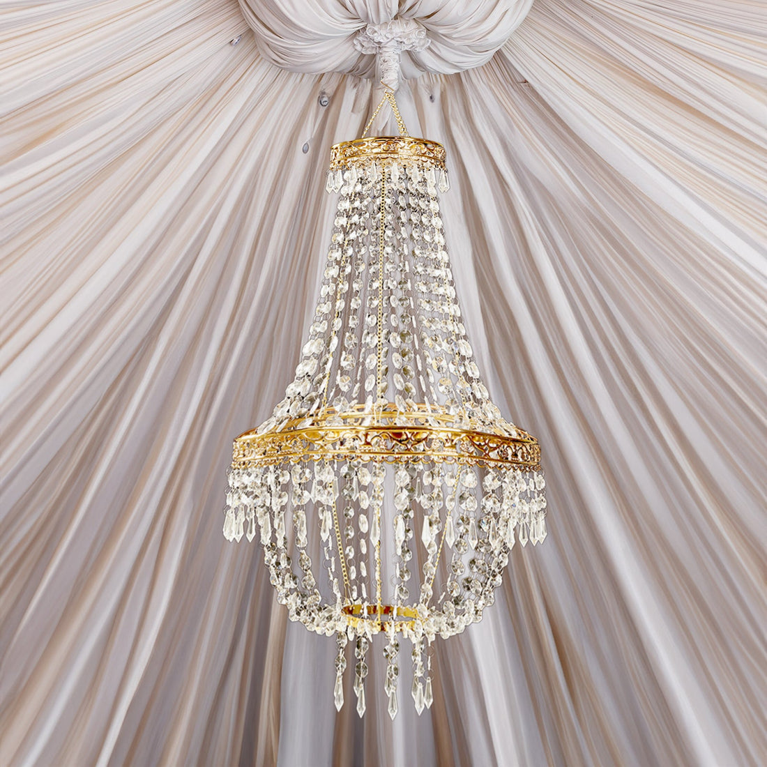 Elegant crystal chandelier with gold accents hanging from a draped ceiling.