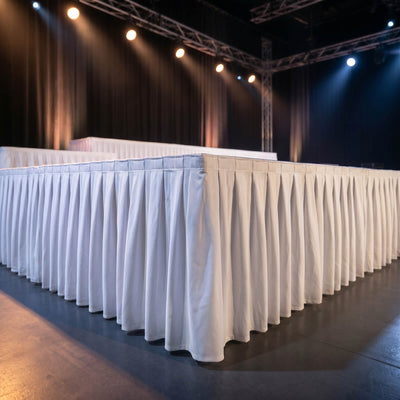 Empty event stage with draped tables and spotlights under truss lighting