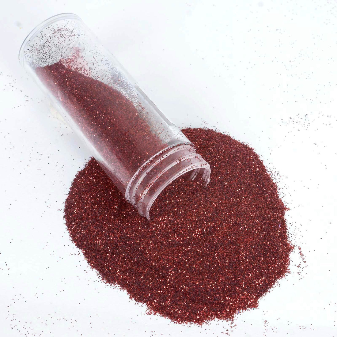 Red glitter spilling from a clear container on a white background. #whtbkgd