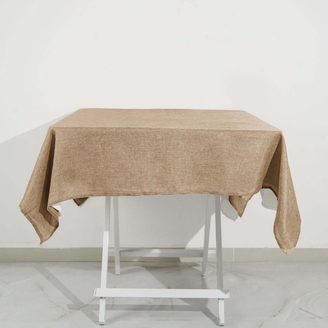 Brown linen tablecloth draped on a white folding table.