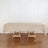 Beige tablecloth draped over a wooden table in a minimalist setting.