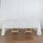 White tablecloth draped over a wooden table with a simple design.
