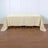 Plain beige tablecloth draped over a wooden table on a light wooden floor.