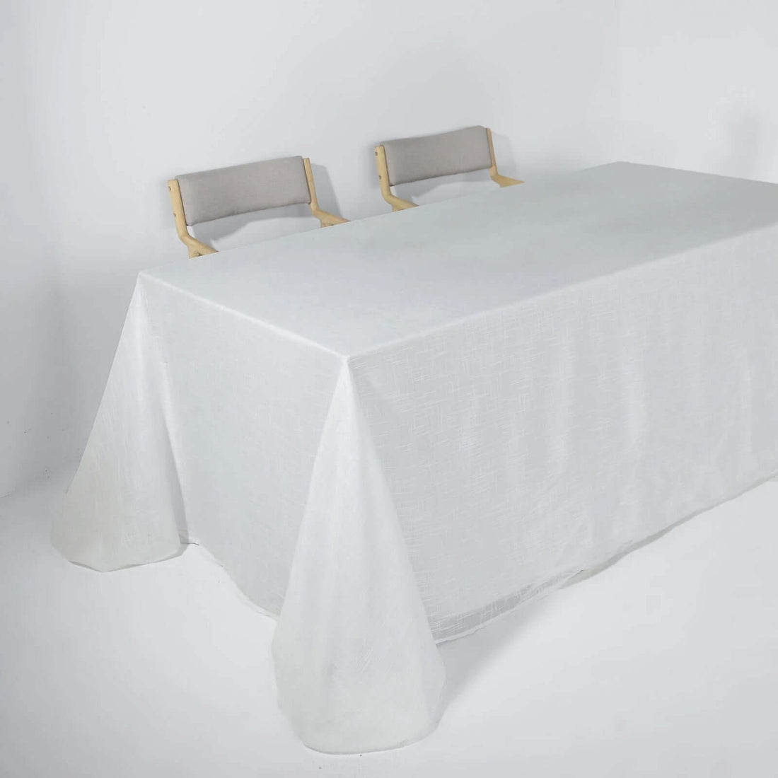 White table with a textured tablecloth and two wooden chairs