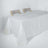 White table with a textured tablecloth and two wooden chairs