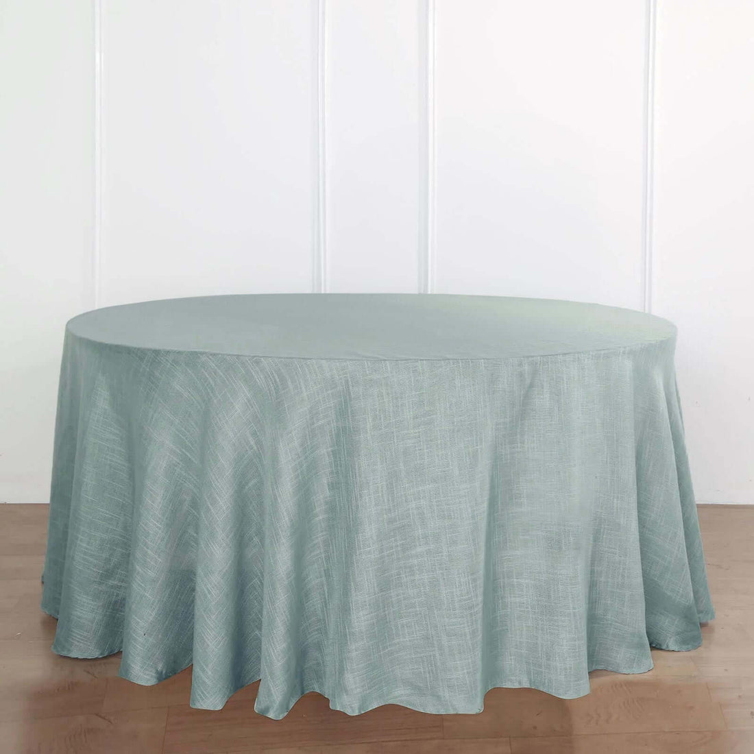 Round light blue tablecloth on a wooden surface.