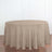 Round beige tablecloth on a wooden table against a white backdrop.