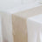 Beige table runner on a white tablecloth, elegant dining setup.