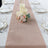 Elegant table runner with candles and floral arrangement on a dining table.