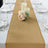 Elegant burlap table runner with candles and floral arrangement on a dining table.