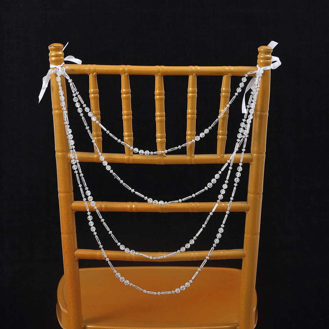 Crystal bead garland draped over a gold chiavari chair.