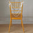 Gold chiavari chair adorned with white pearl garland and ribbons.