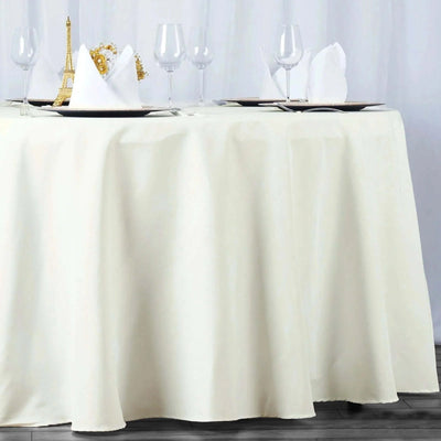 Elegant cream tablecloth draping over a round table set with glassware and napkins.