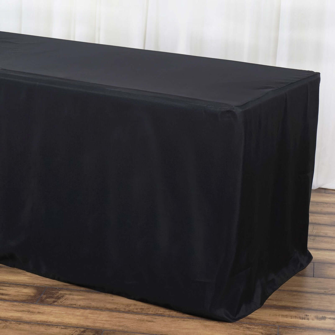 Black tablecloth draped over a table with a wooden floor backdrop.