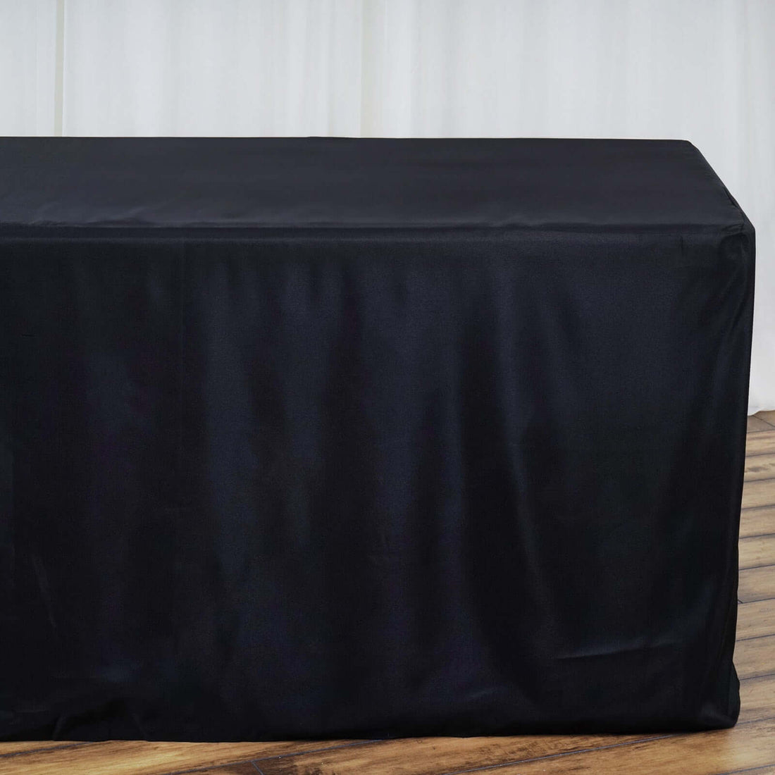Black table cover draped over a table against a light background.