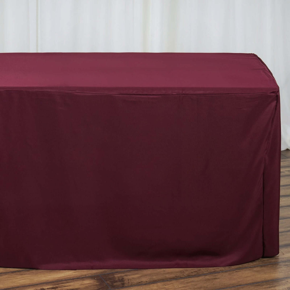 Burgundy table cover on a wooden floor.
