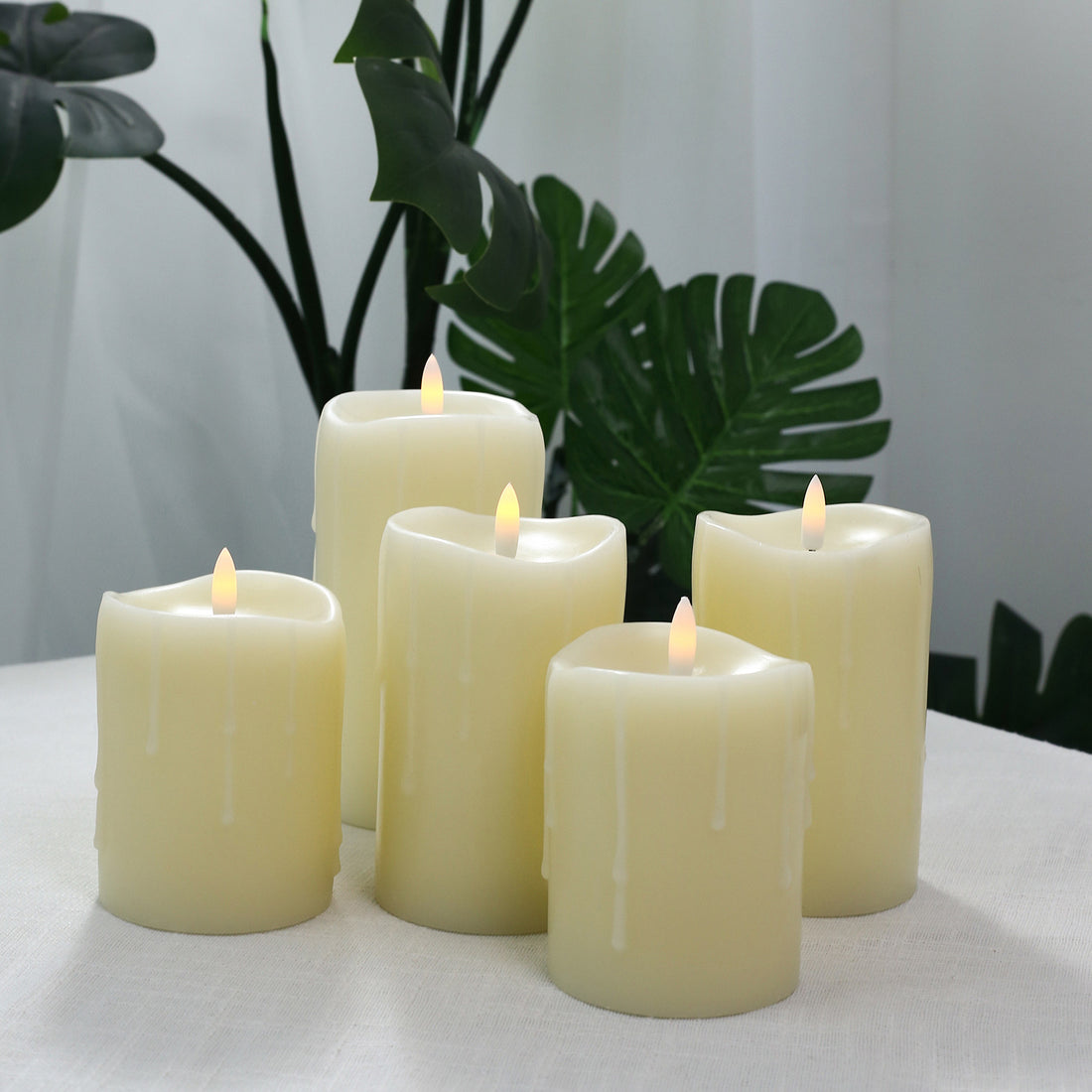 Five flameless LED pillar candles with tropical green leaves background