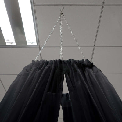 Black sheer curtain hanging from a chain in a ceiling mount.