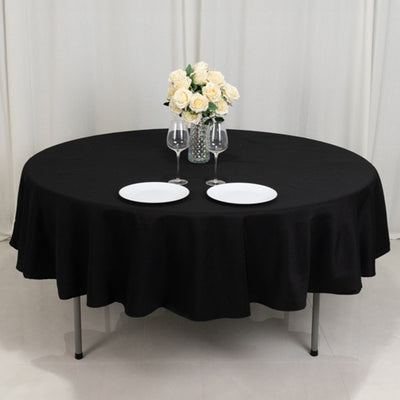 Round black table with two plates and a vase of roses.