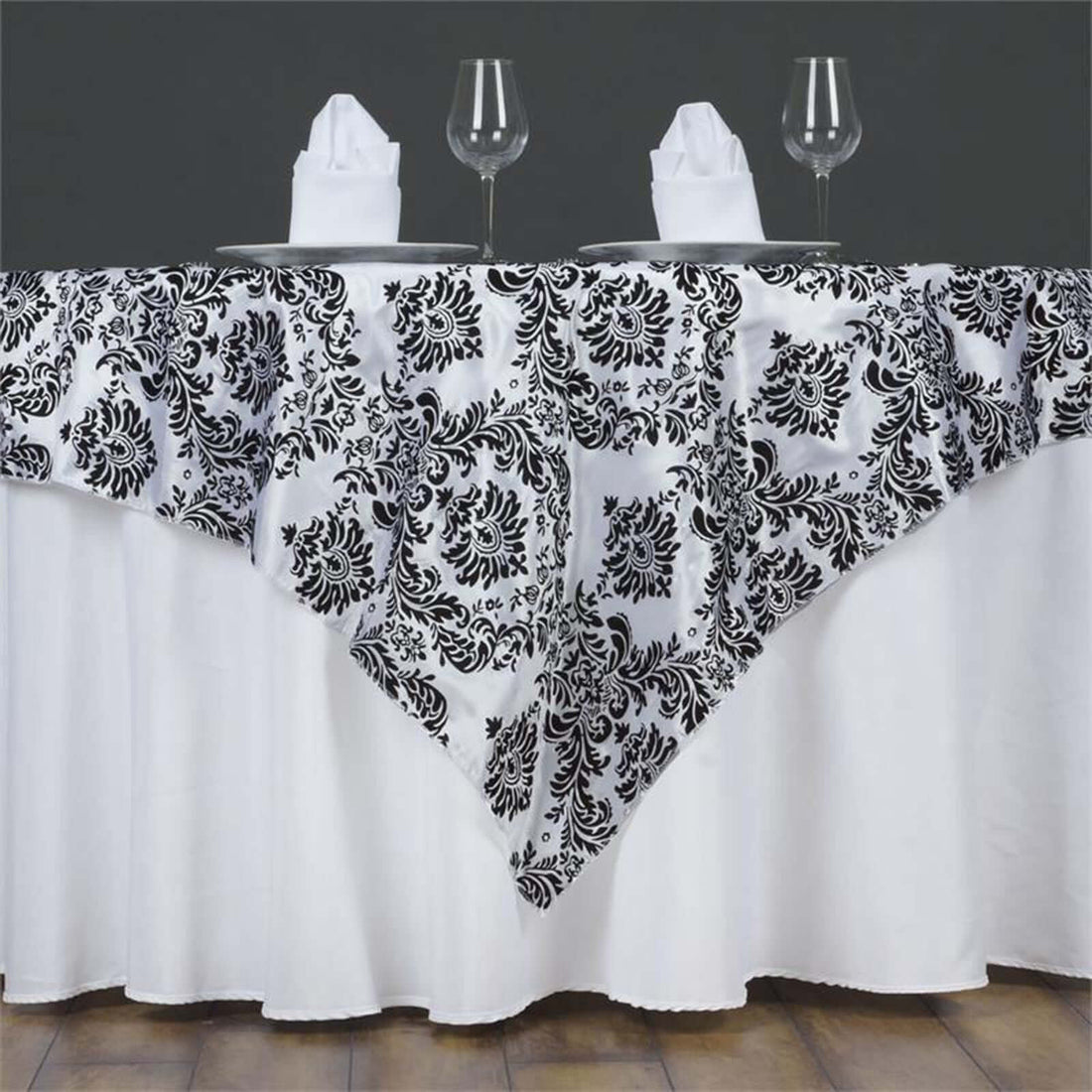 Black and white floral tablecloth draped over a table with dinnerware.
