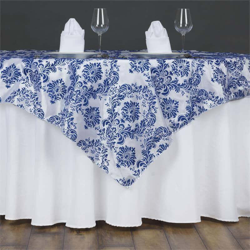 Blue and white floral tablecloth on a dining table with napkins and glasses.