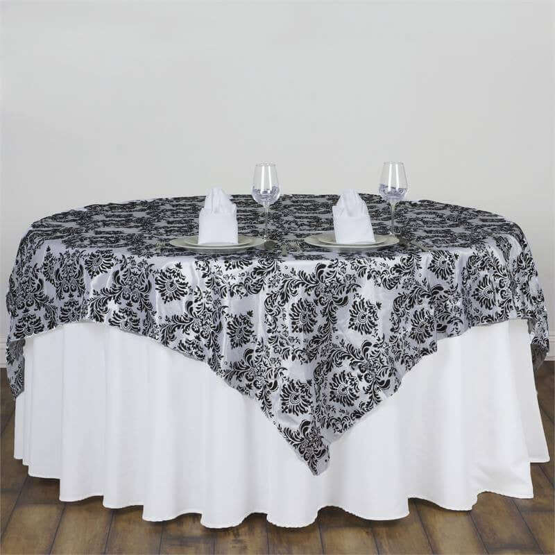 Elegant black and white tablecloth draped over round table with glassware.
