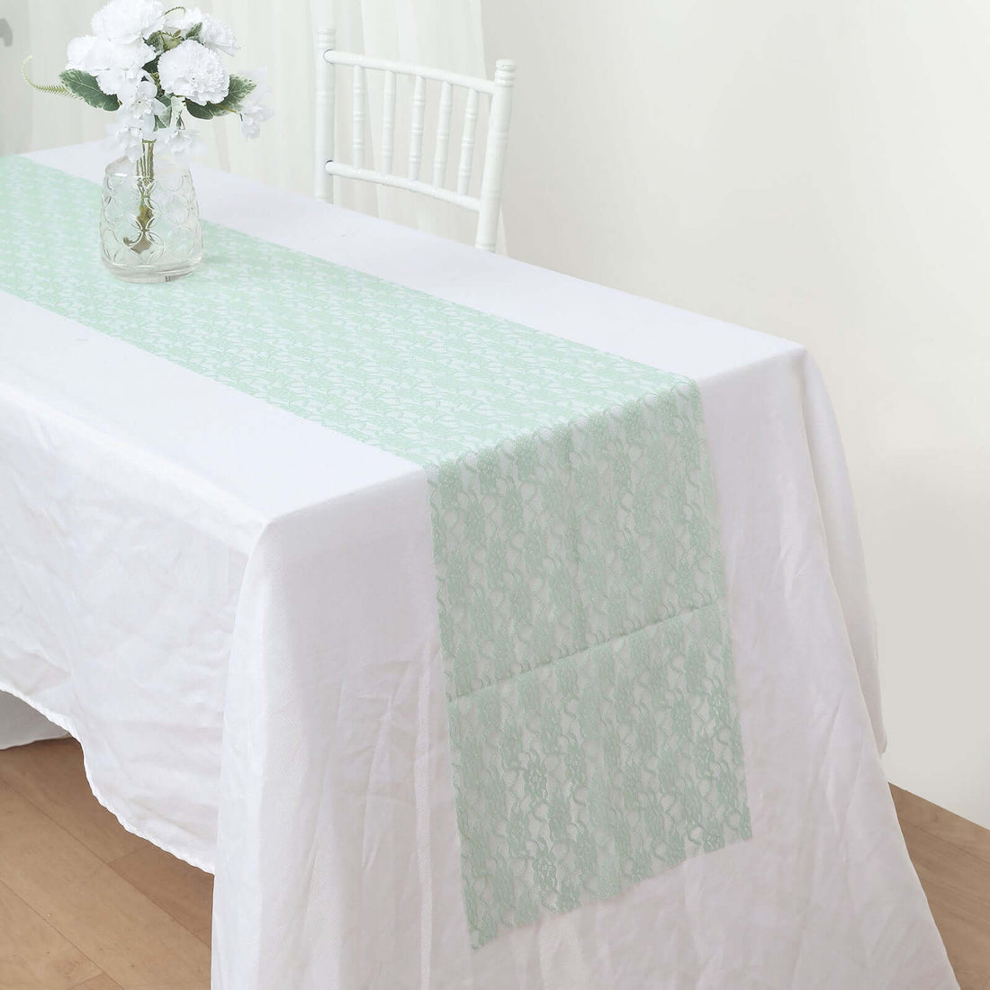 Mint green lace table runner on a white tablecloth.