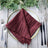 Burgundy pleated napkin elegantly placed on a decorative plate. #whtbkgd