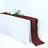 Burgundy table runner draped over a white table with floral centerpiece and glasses