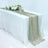 Elegant beige table runner on a white table with floral decor and candles.
