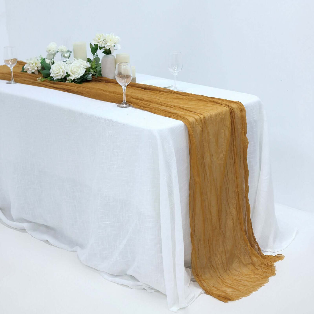 Elegant gold table runner on a white table with floral decor and glassware.