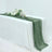 Elegant green table runner on a white table with floral decor and glasses.