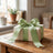 Gift box with green ribbon bow on wooden table in a cozy room