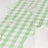 Green checkered tablecloth with wine glasses and white napkin on a dining table.