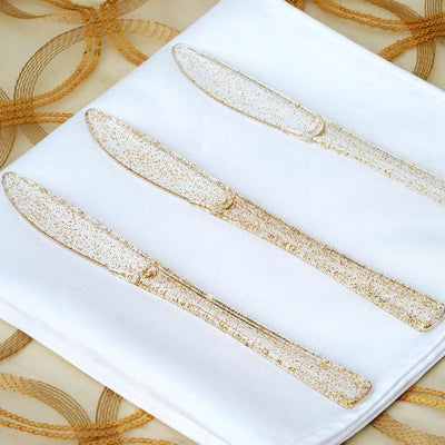 Gold glitter knives on a white napkin.