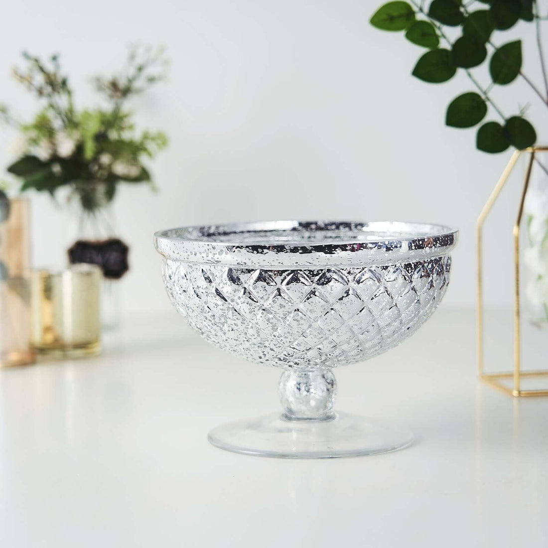 Silver glass bowl with intricate diamond pattern on a plain backdrop.