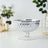 Silver glass bowl with intricate diamond pattern on a plain backdrop.
