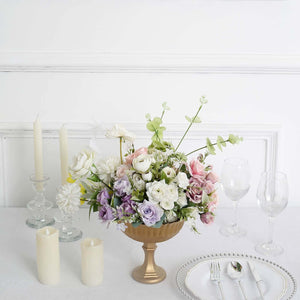 Elegant floral arrangement in a gold vase with candles and tableware
