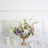 Elegant floral arrangement in a gold vase with candles and tableware