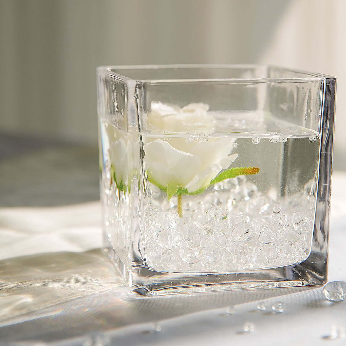 Clear glass vase with white roses and water, showcasing elegant floral arrangement.