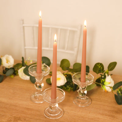 Elegant glass candle holders with tapered candles and floral accents.