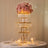 Elegant flower centerpiece with cascading glass tiers and soft lighting.