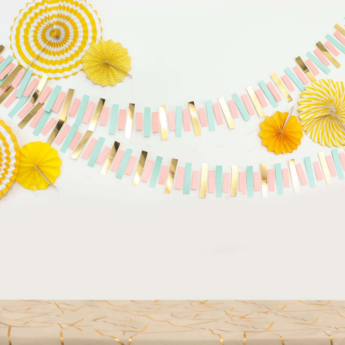 Colorful party decorations with paper fans and garlands on a neutral background.