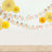 Colorful party decorations with paper fans and garlands on a neutral background.