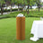 Elegant cylindrical table with flowers, set in a lush outdoor garden scene.