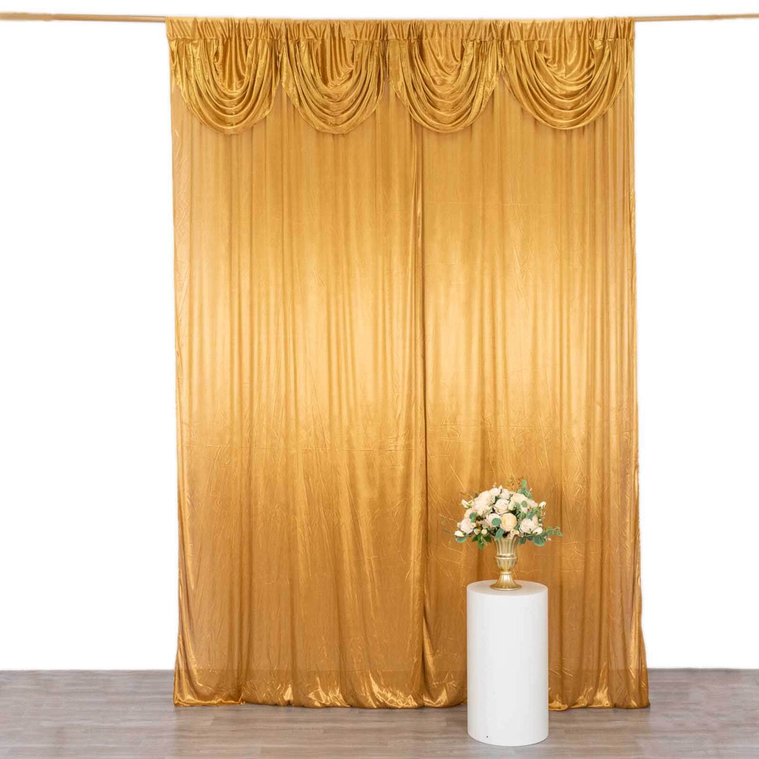 Gold drapery backdrop with decorative pleats and a floral arrangement
