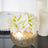 Gold vase with white artificial flowers on reflective table