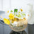 Gold vase with white and yellow flowers arranged elegantly.